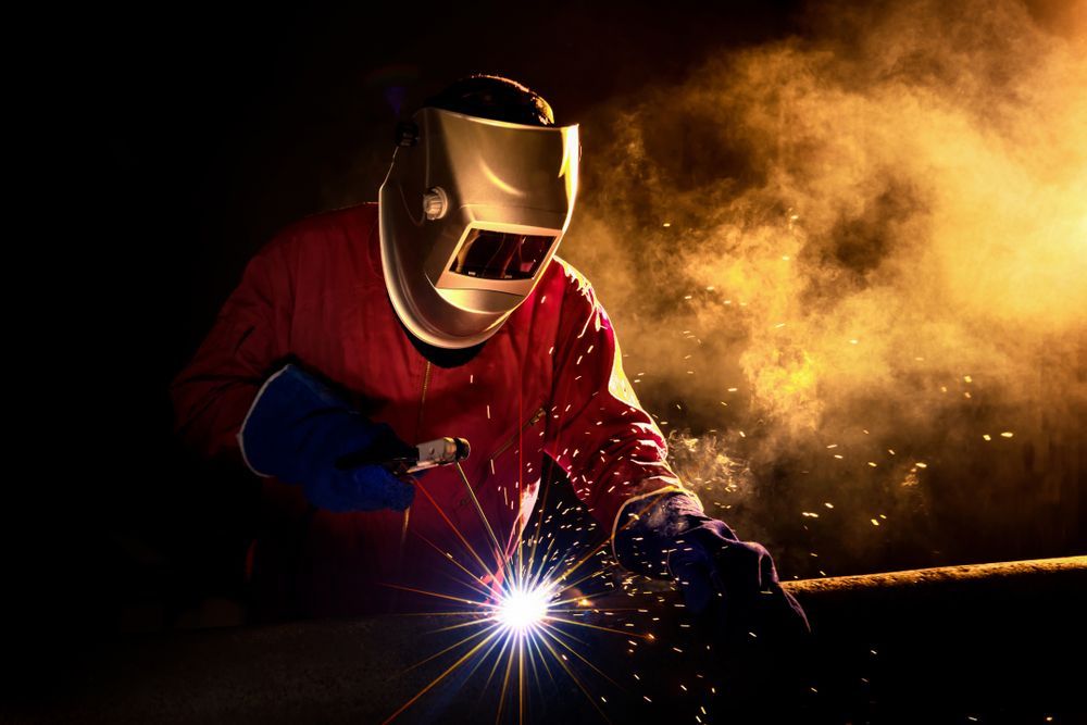 Welder In Protective Gear, Sparks Flying From Welding Rod — Mears Construction & Training Pty Ltd in South Johnstone, QLD