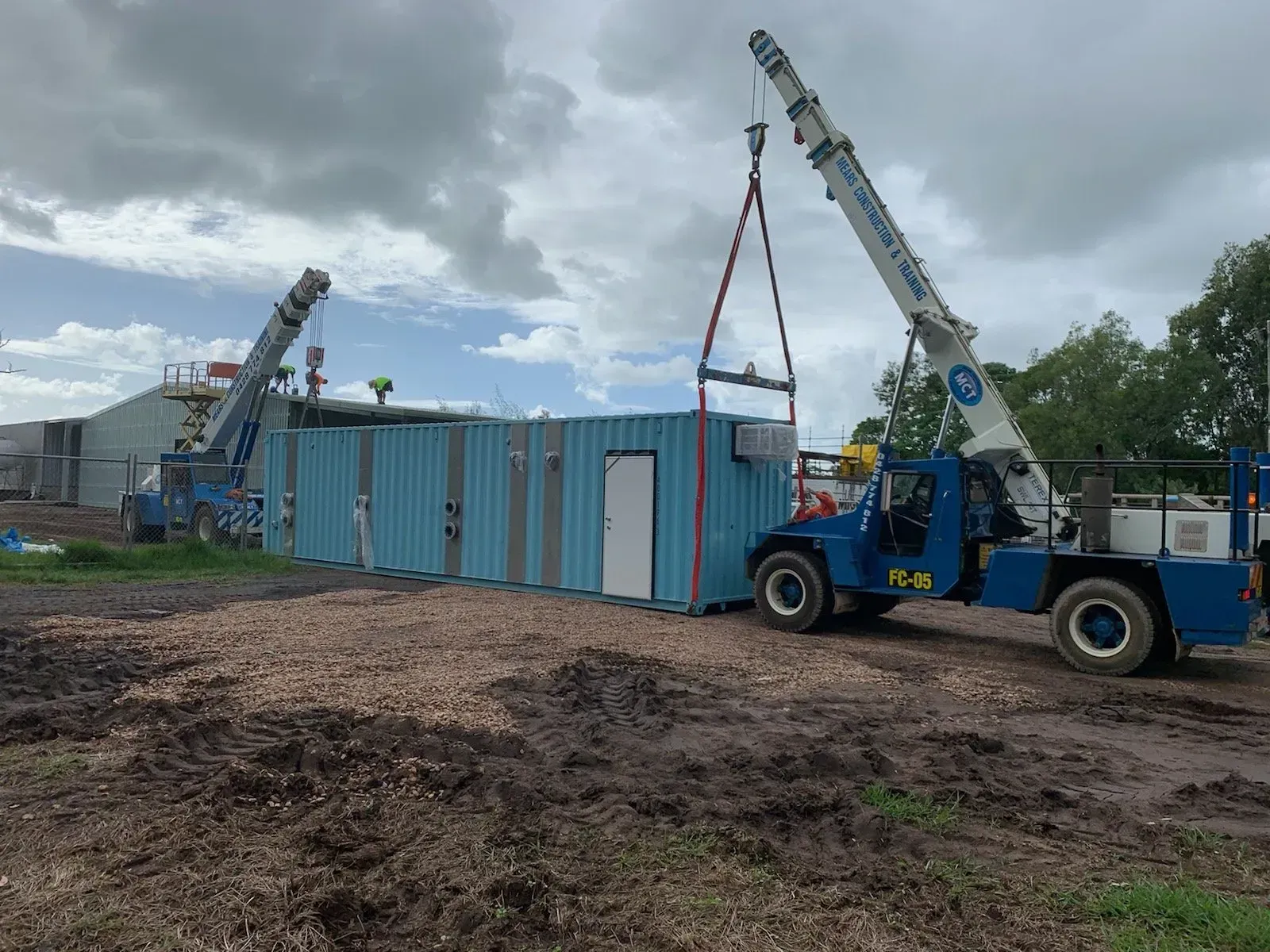 Two Cranes Lifting A Light Blue Utility Building — Mears Construction & Training Pty Ltd in South Johnstone, QLD