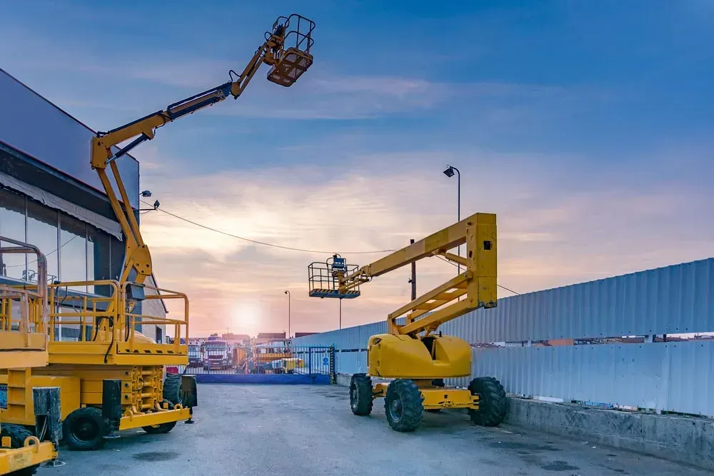 Two Yellow Boom Lifts, One With A Worker, Outdoors Against A Cloudy Sky — Mears Construction & Training Pty Ltd in Tully, QLD