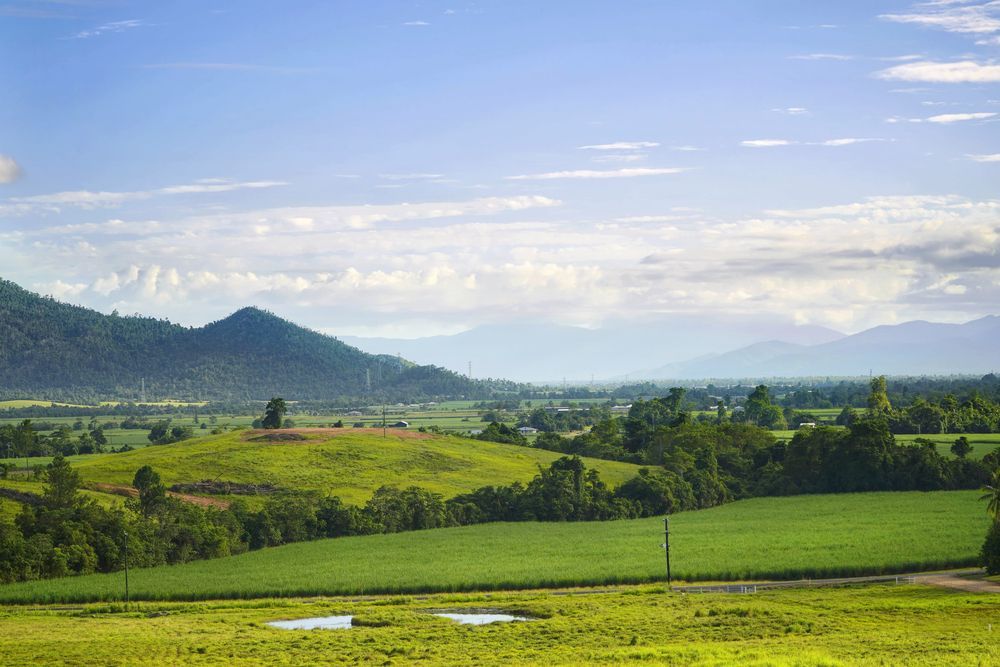 Green Fields And Hills Under A Partly Cloudy Blue Sky — Mears Construction & Training Pty Ltd in Tully, QLD