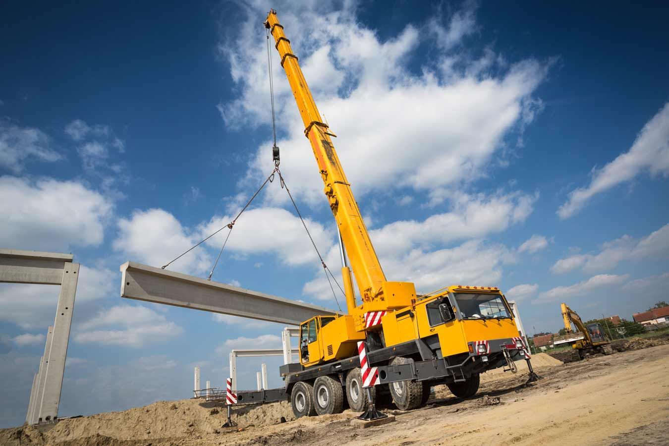 Yellow Crane Lifting A Concrete Beam At A Construction Site — Mears Construction & Training Pty Ltd in Innisfail, QLD