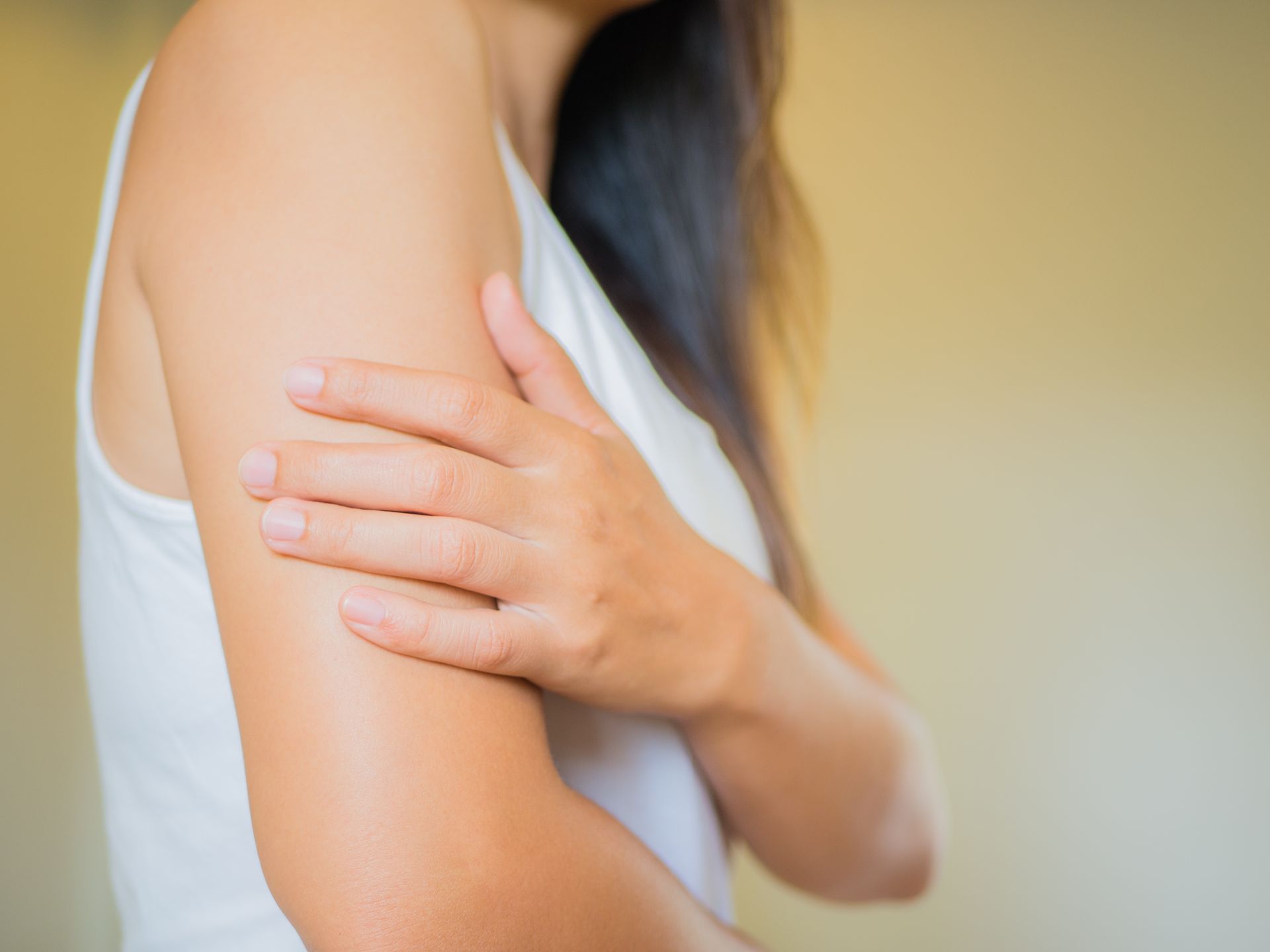 A woman is holding her arm in pain.