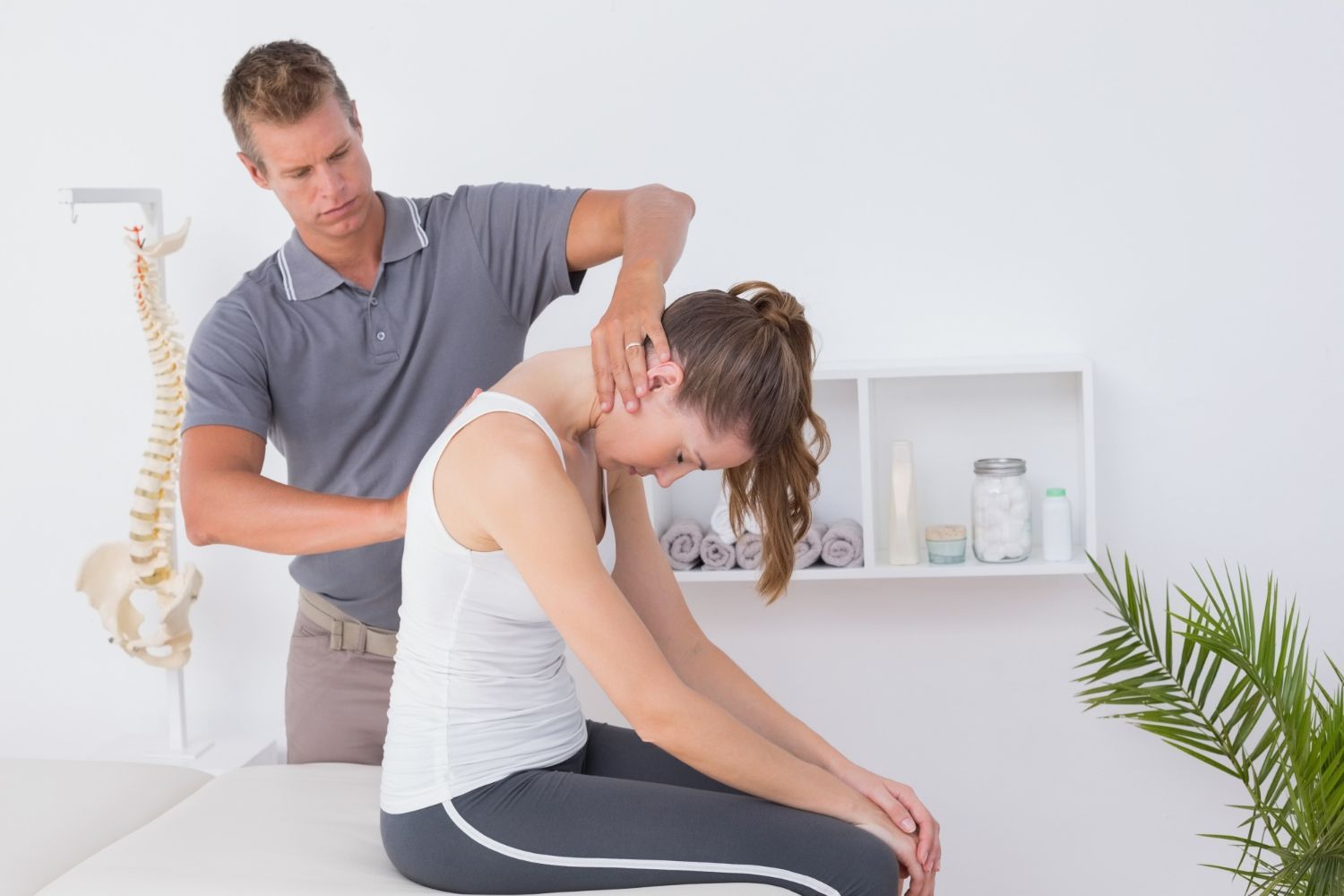 A man is examining a woman 's neck while she sits on a table.