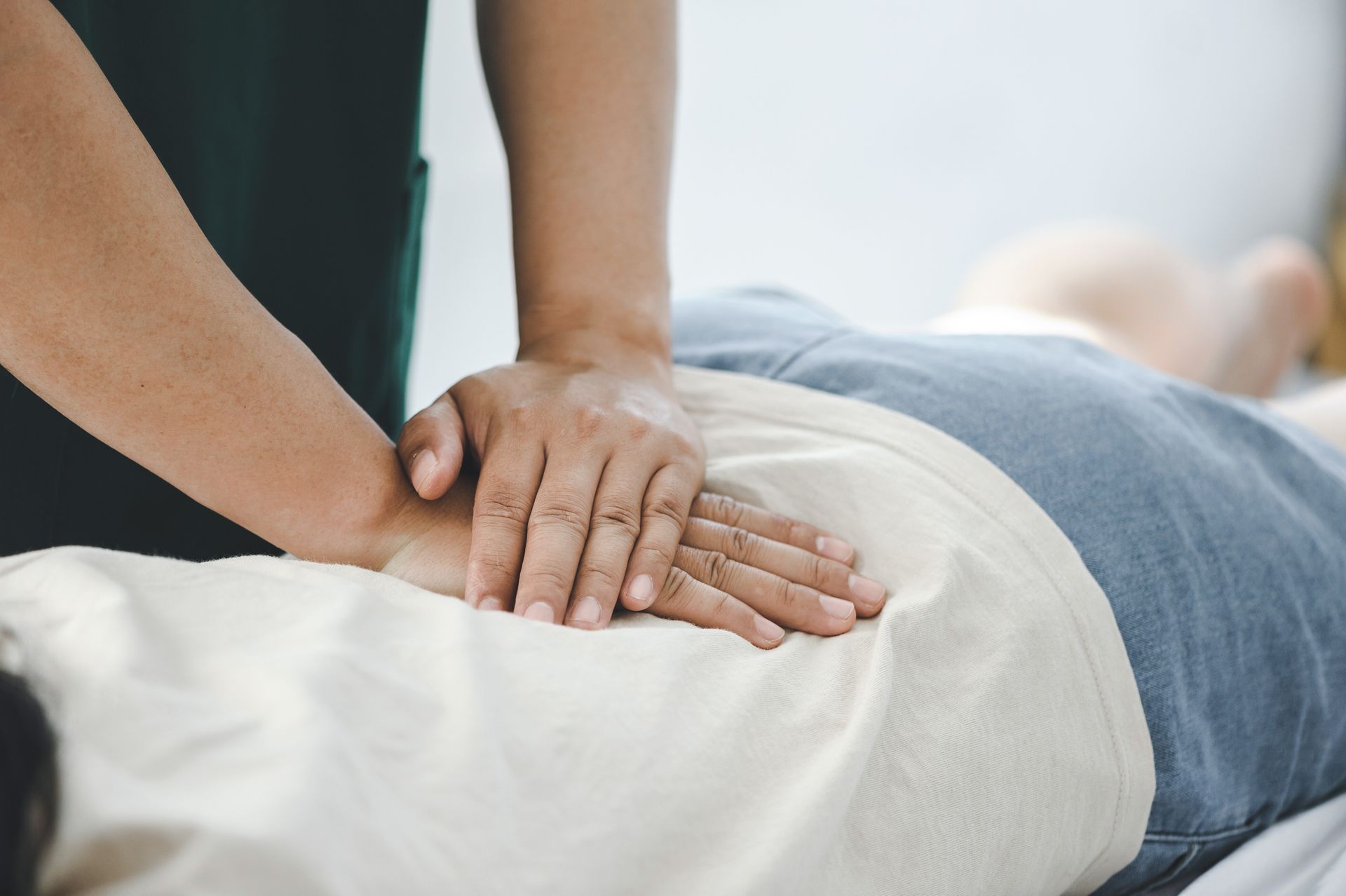 Hands performing back massage on a person lying face down.