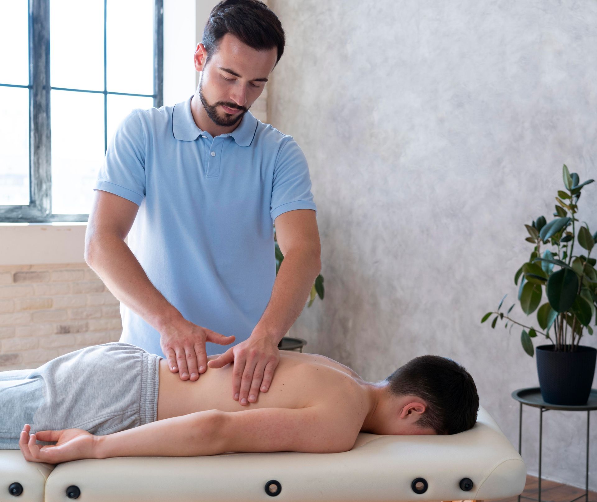 Man giving back massage to another man on a massage table.