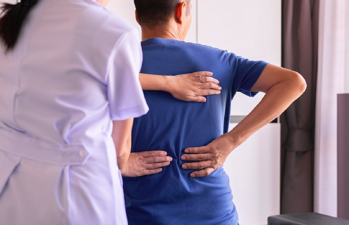 A nurse is helping a man with his back pain.