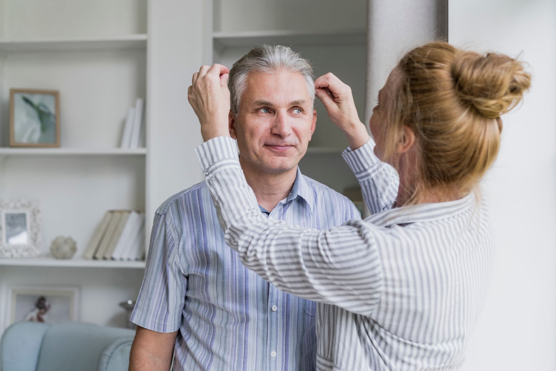 A woman is putting a wig on a man 's head.