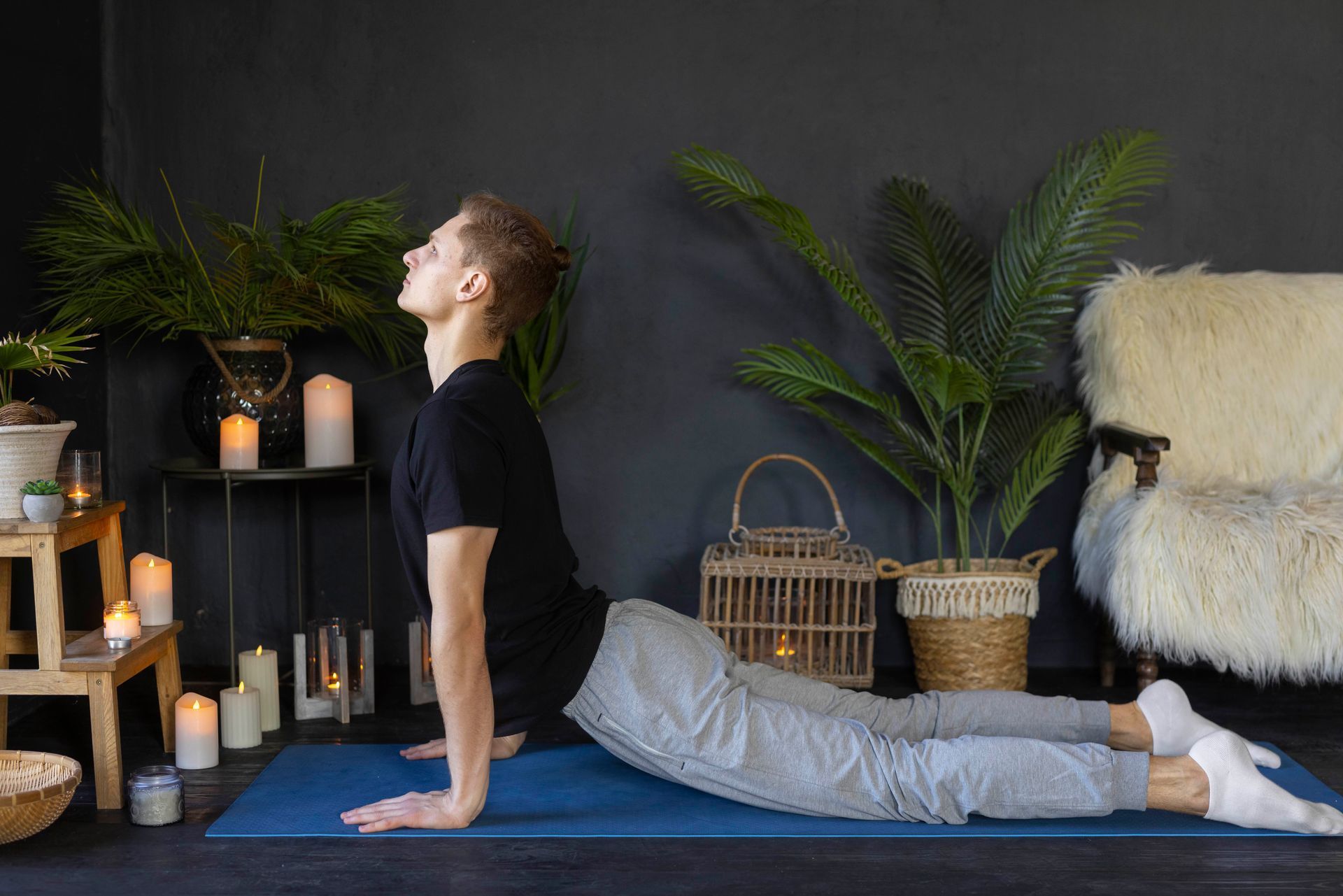 A man is doing yoga on a blue mat in a living room.