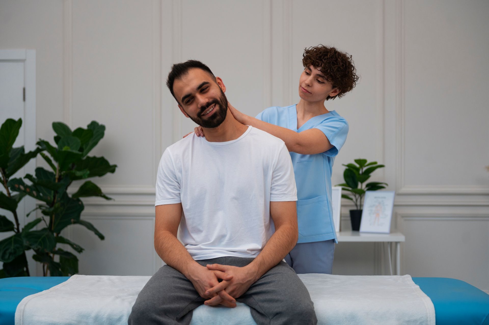 A man is sitting on a massage table while a woman massages his neck.