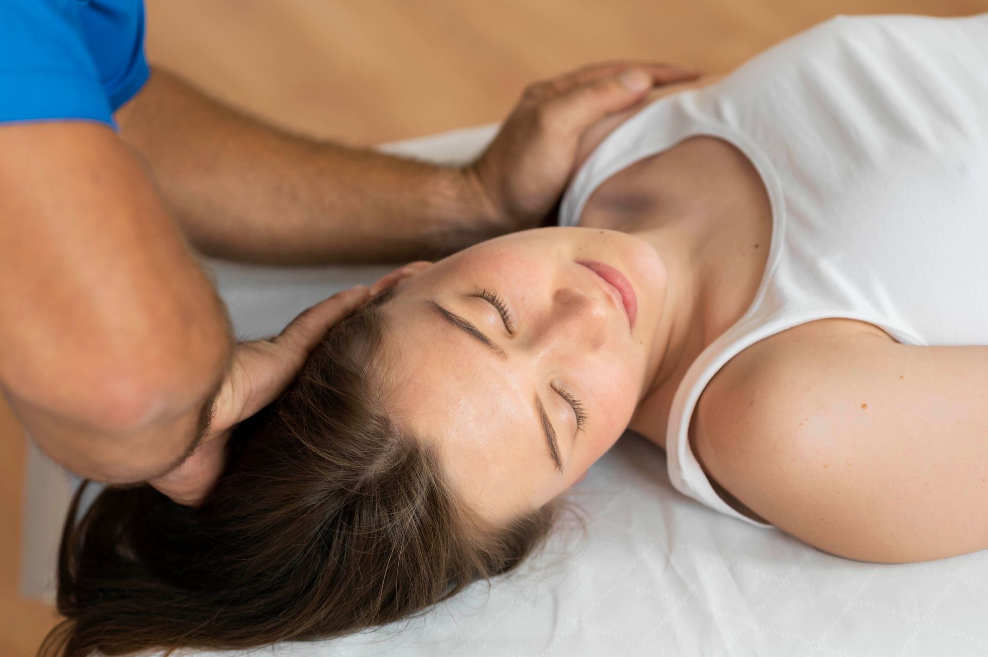 A woman is laying on a bed getting a head massage from a man.