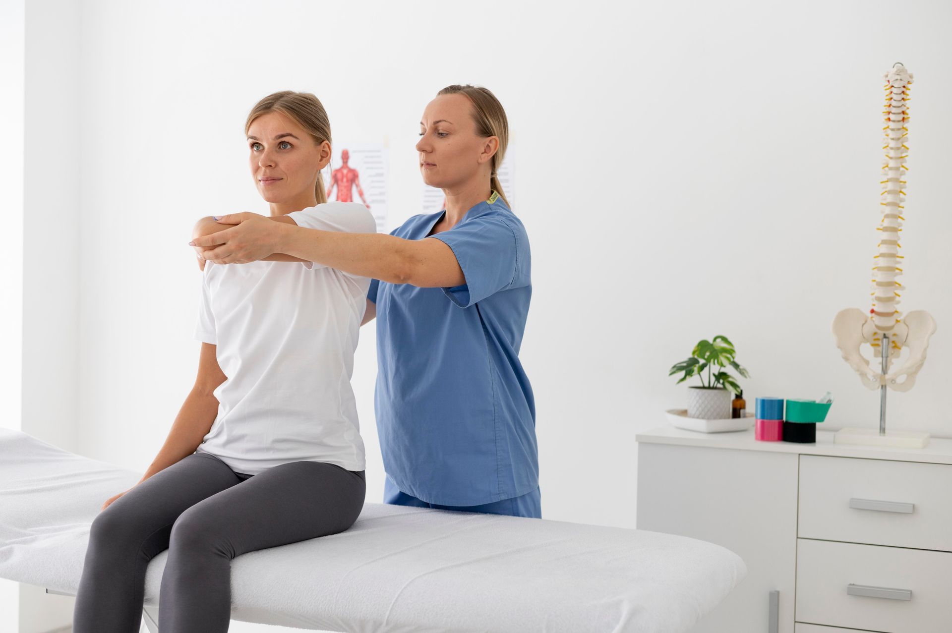 A woman is sitting on a table while a doctor examines her back.