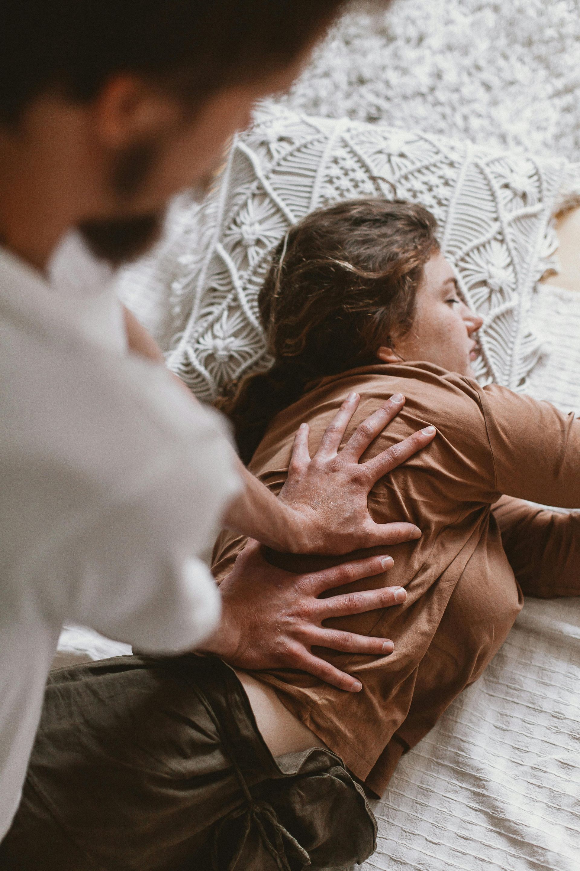 A man is giving a woman a massage on a bed.