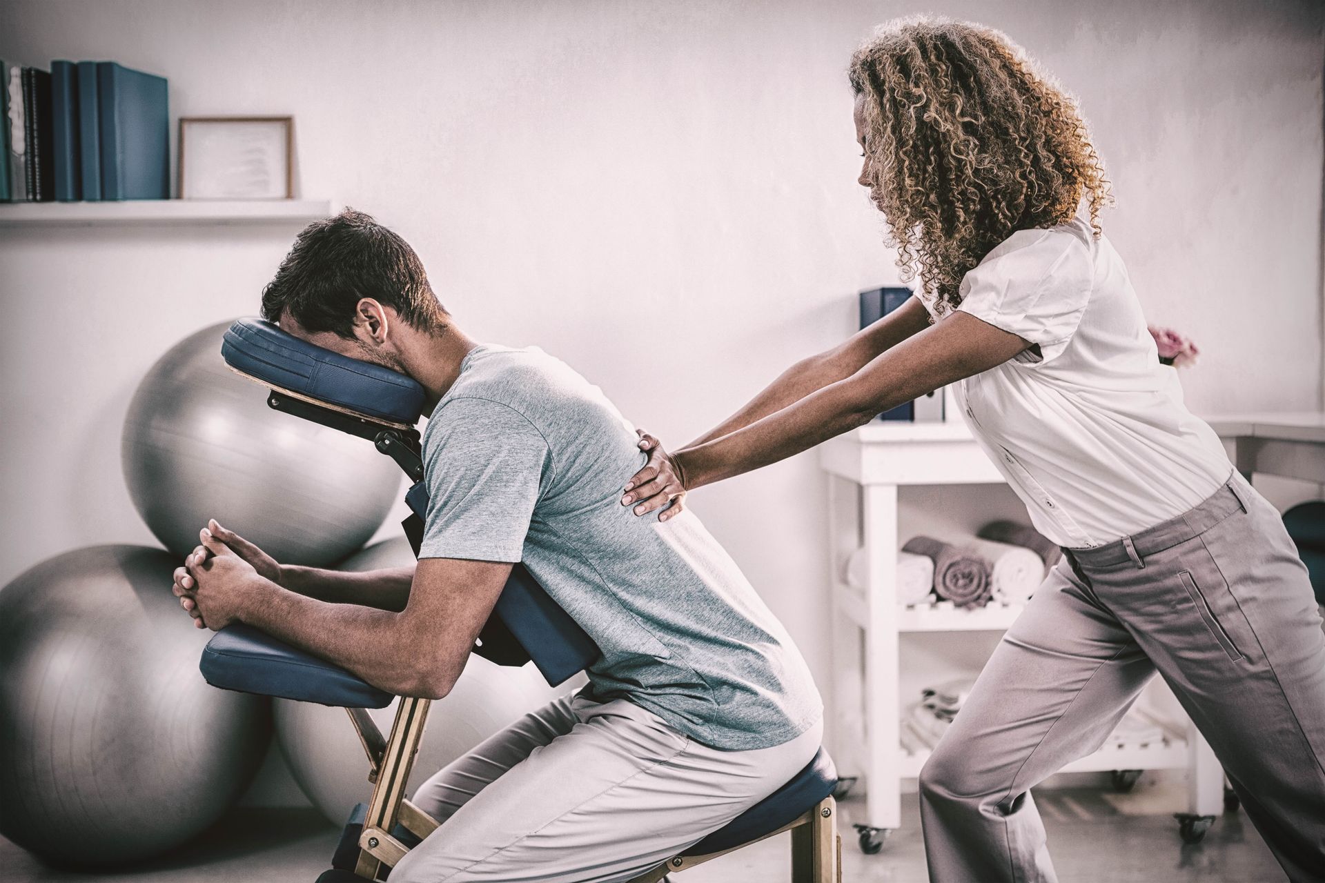 A woman is giving a man a massage in a chair.