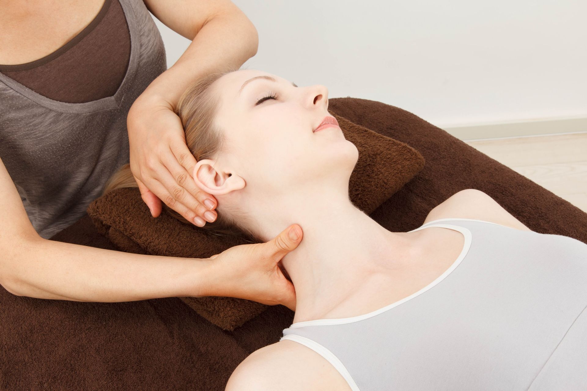 A woman is laying on a bed getting a massage on her neck.