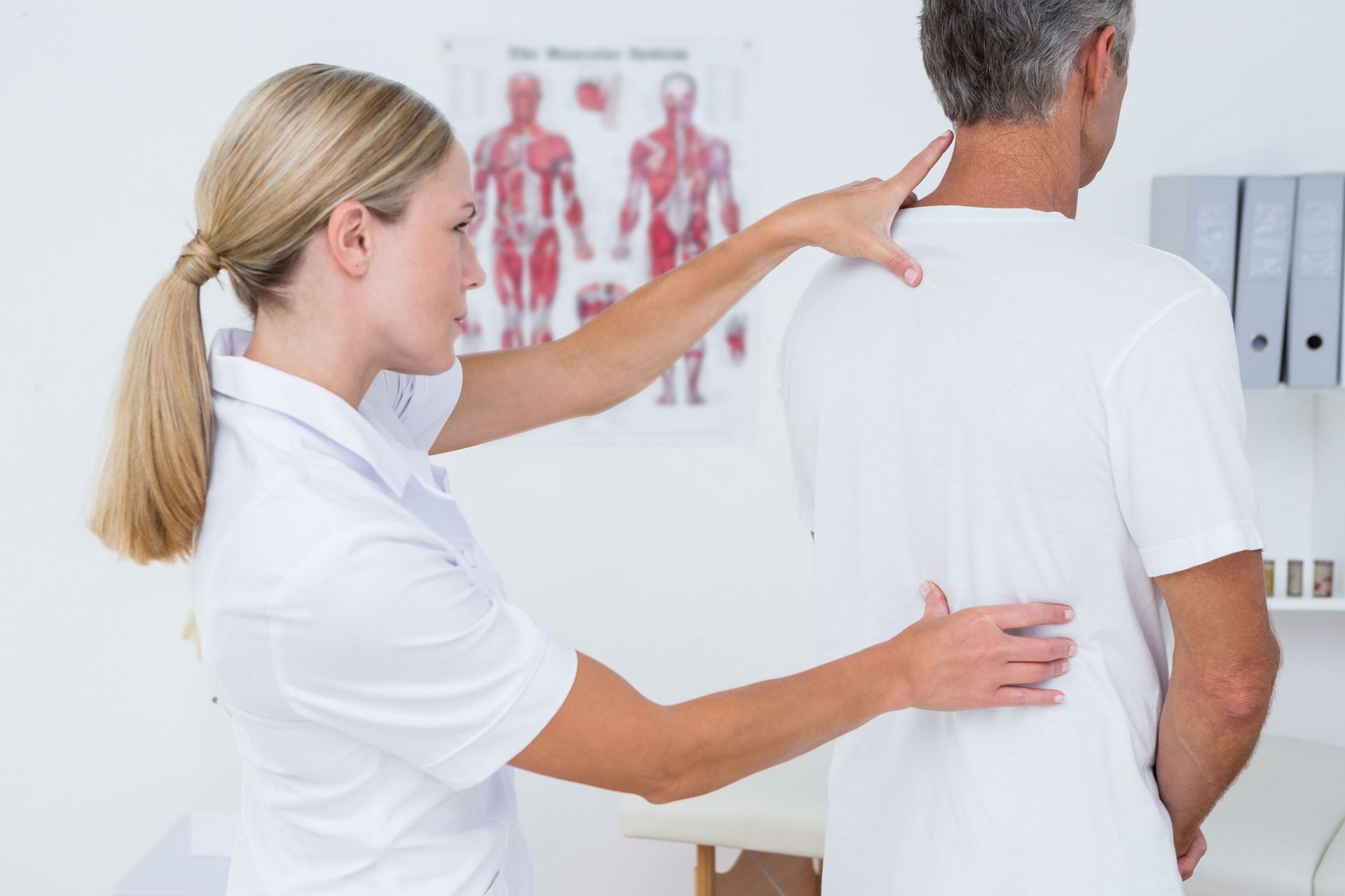 A nurse is examining a man 's back in a hospital.