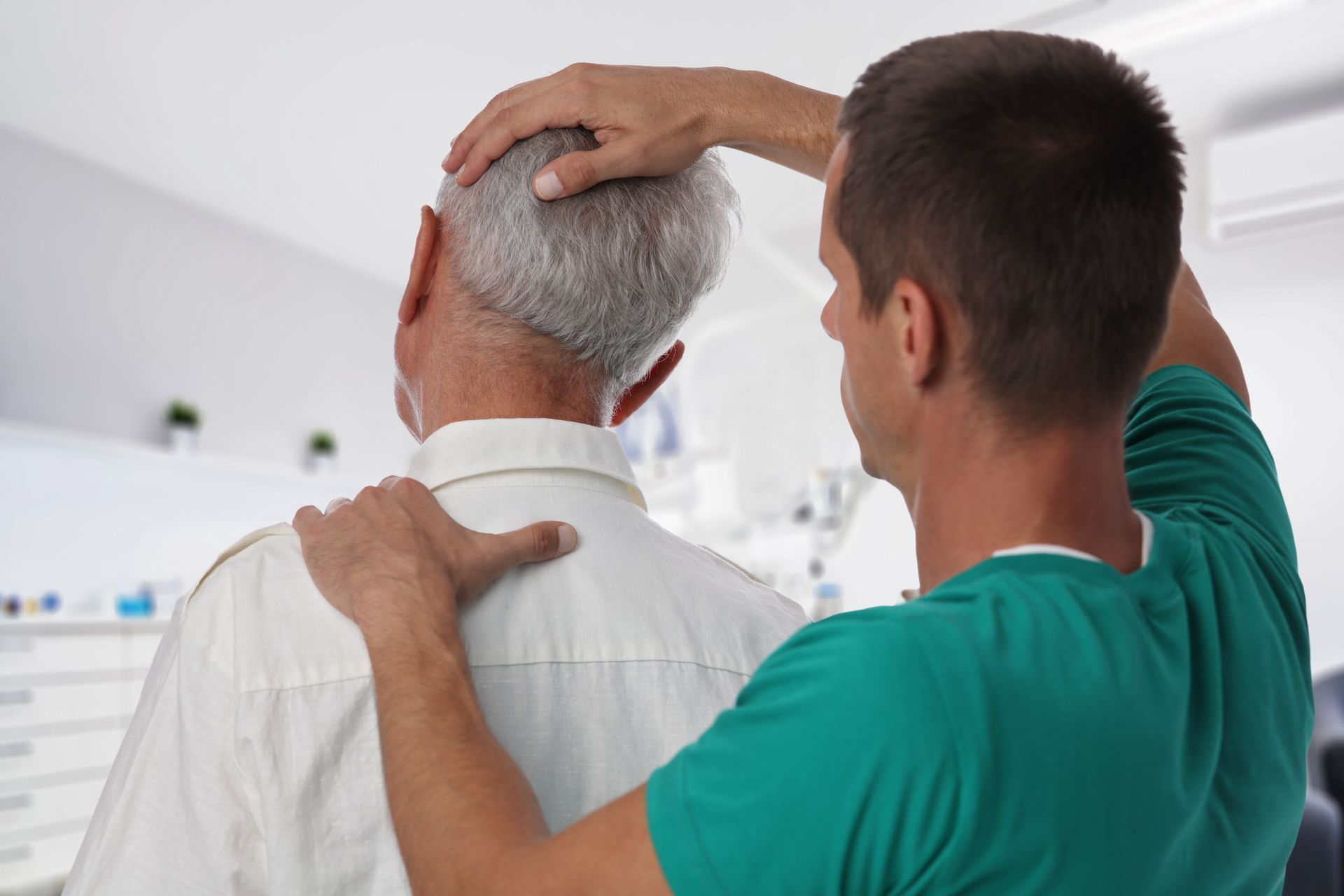 A nurse is helping an elderly man with his head.