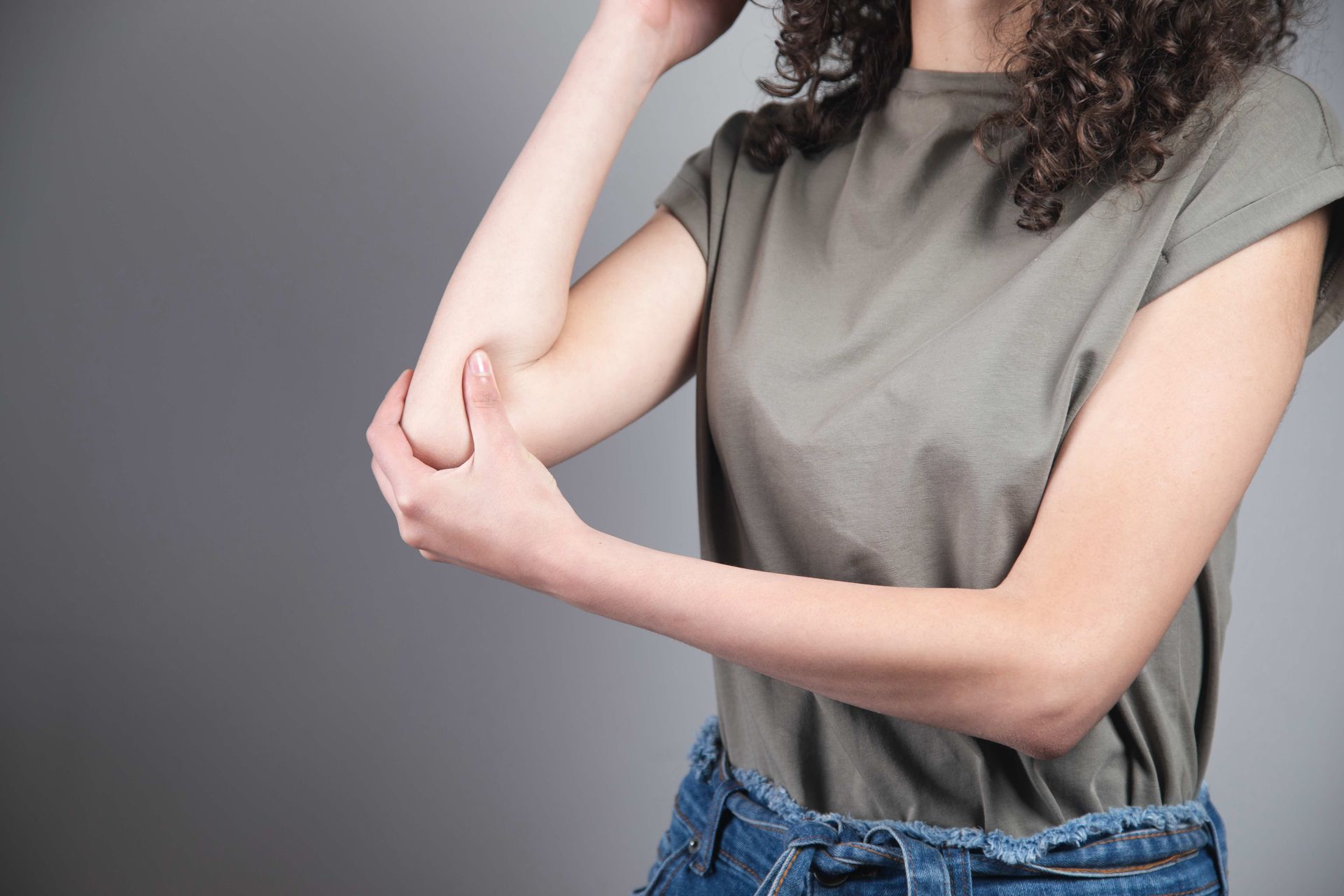 A woman is holding her elbow in pain.