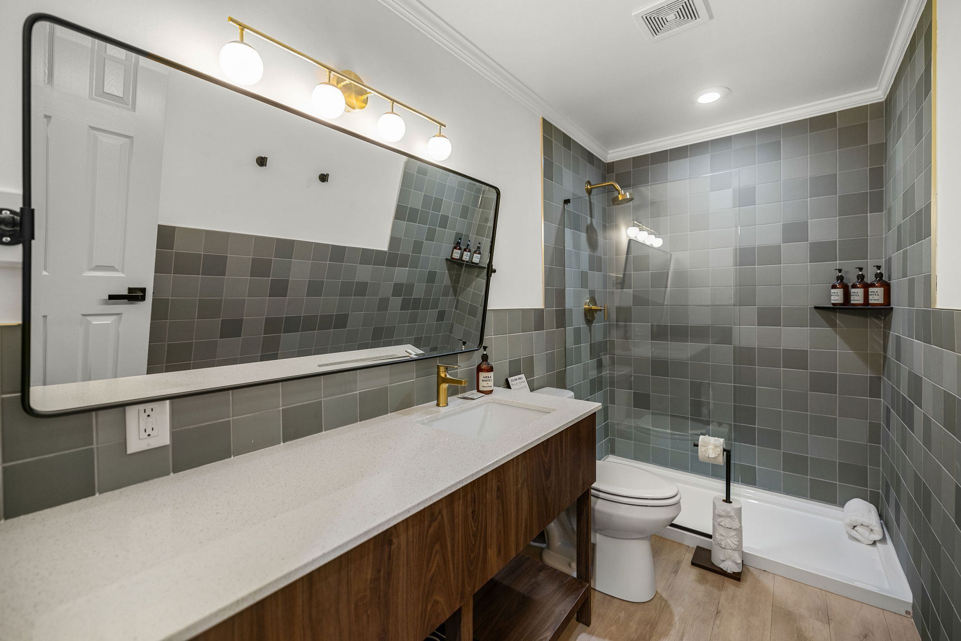 Spacious bathroom in two-bedroom unit with walk-in shower and single-sink vanity at Arka Motel.