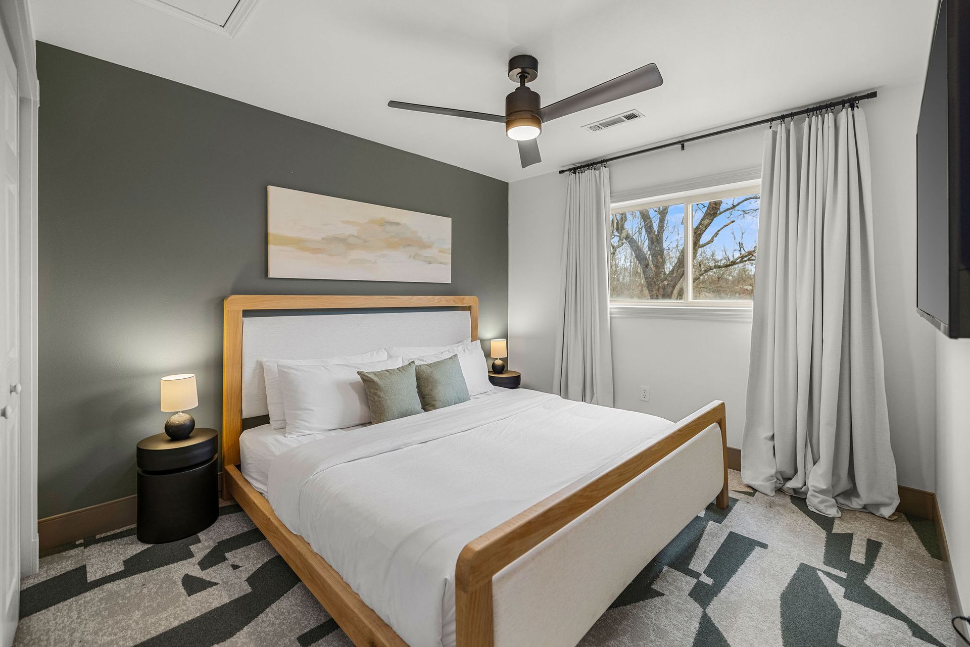 Cozy queen bedroom with ceiling fan and modern decor.