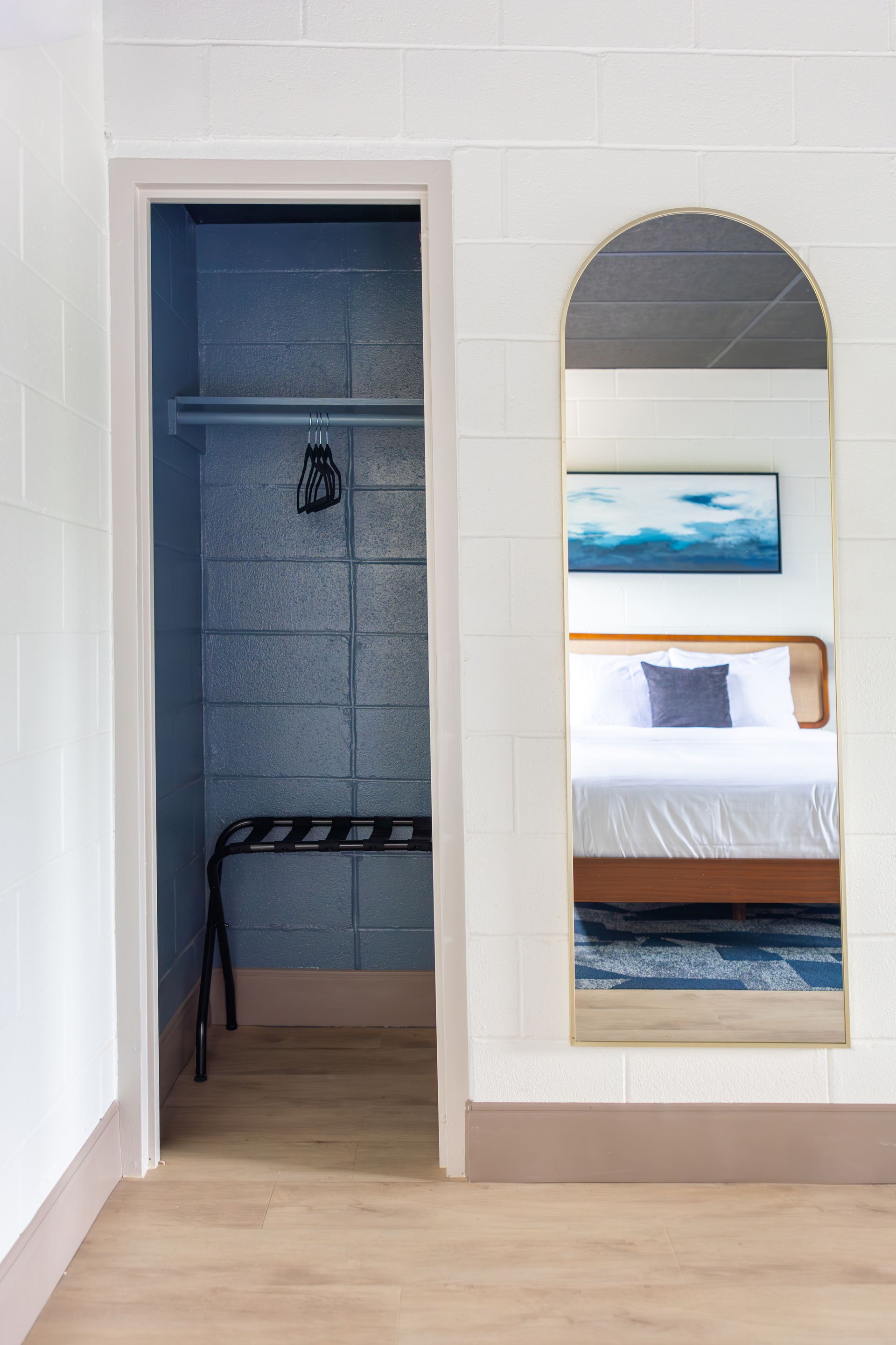 The closet for clothing storage and a luggage rack with a view of the room in the mirror.