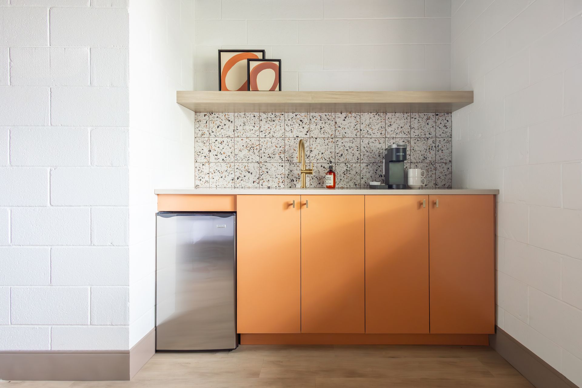 A kitchen with pink cabinets , a sink , and a coffee maker.