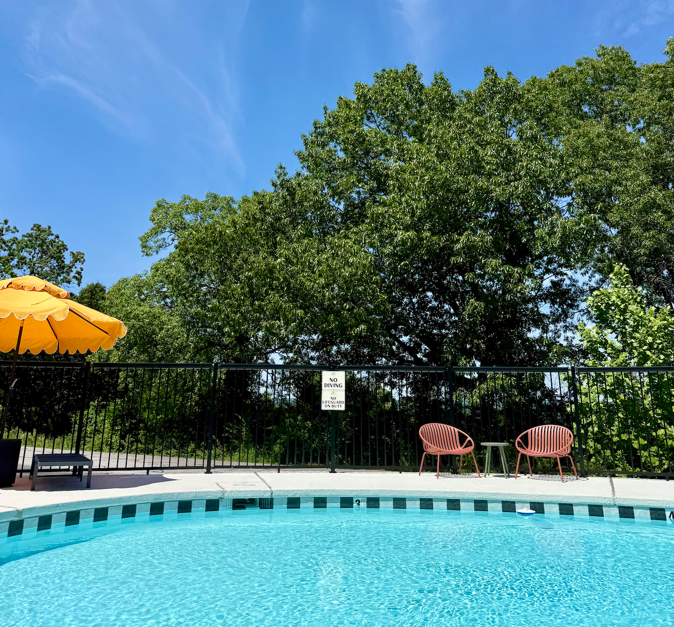 A swimming pool with a yellow umbrella and chairs