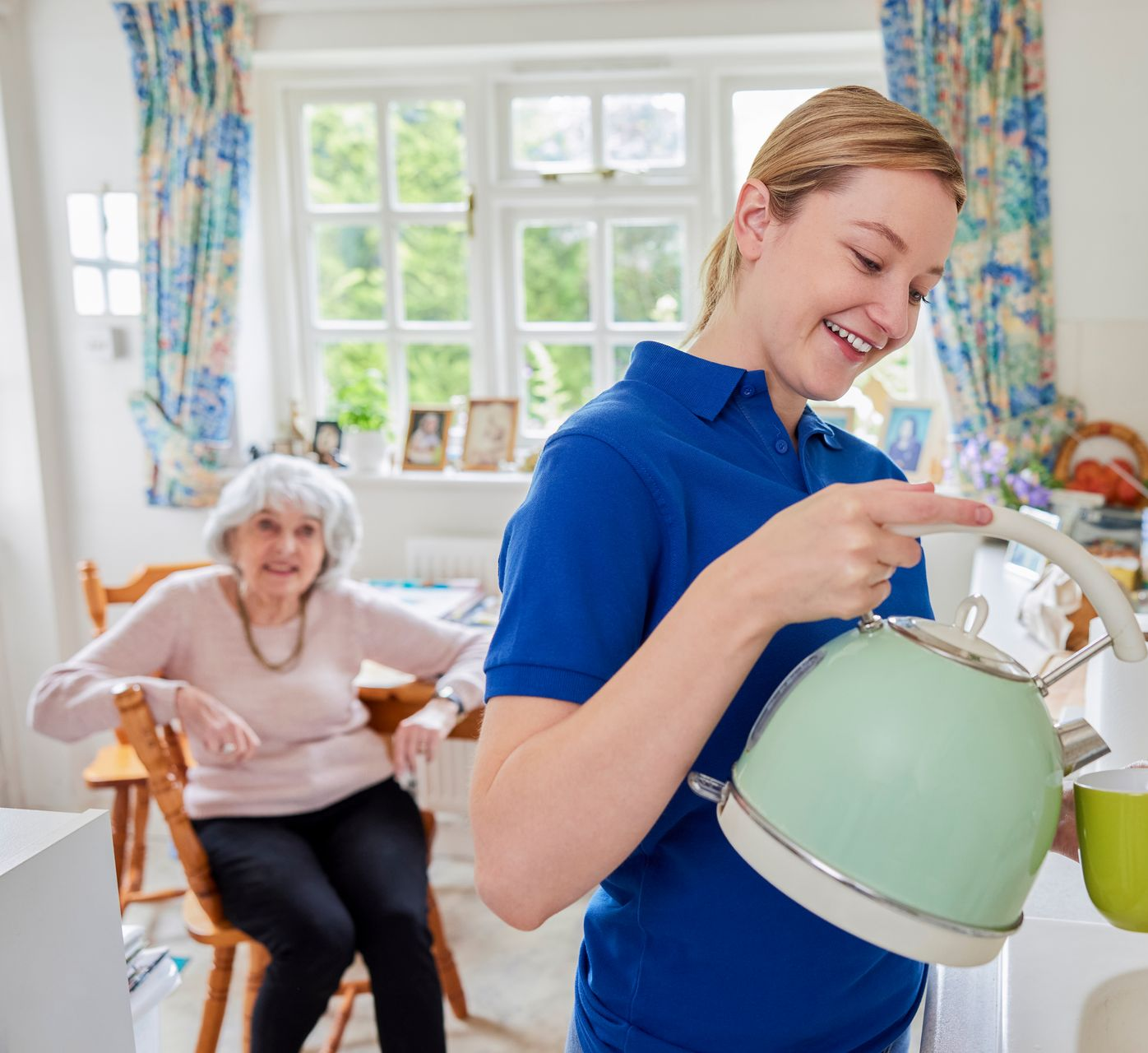 Support worker helping an elderly woman with household tasks at home