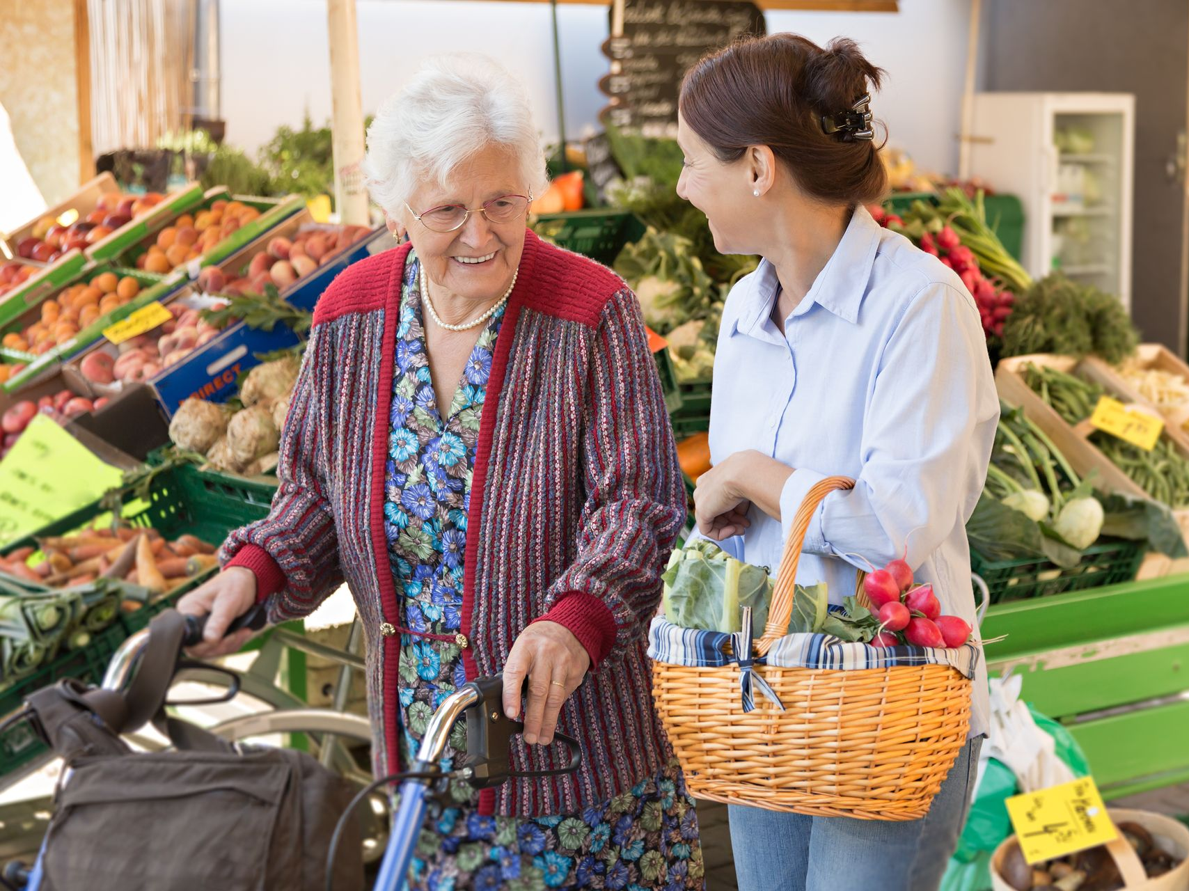 Companion support worker helping an elderly woman with her shopping at a local market