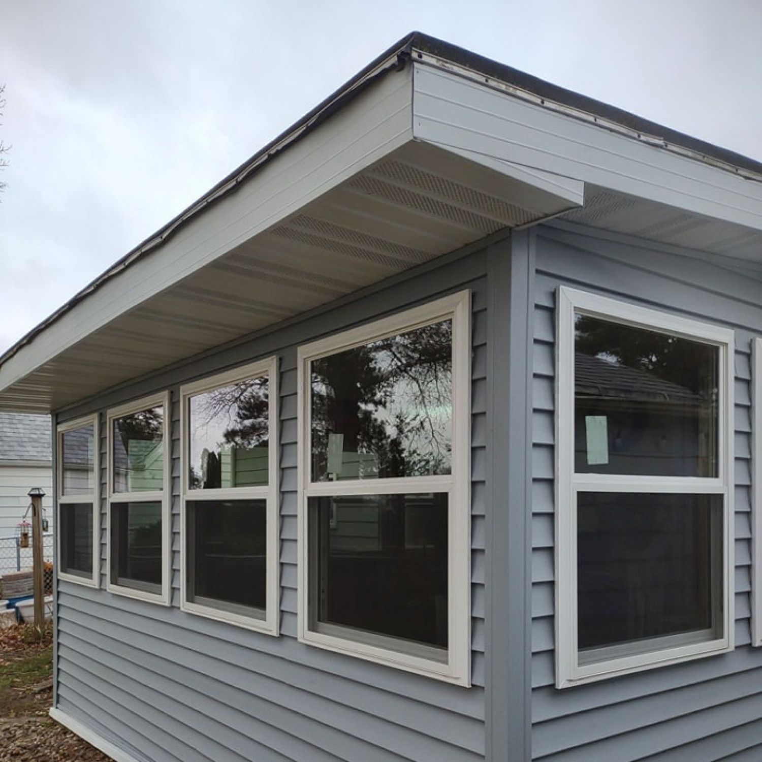 Light blue siding on a building with multiple white-framed windows under a gray roof.