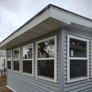 Light blue siding on a building with multiple white-framed windows under a gray roof.