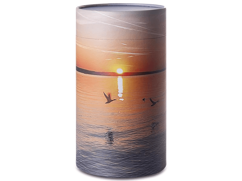 Cylinder urn with a sunset over water scene, featuring birds in flight and sunlight reflecting on waves.