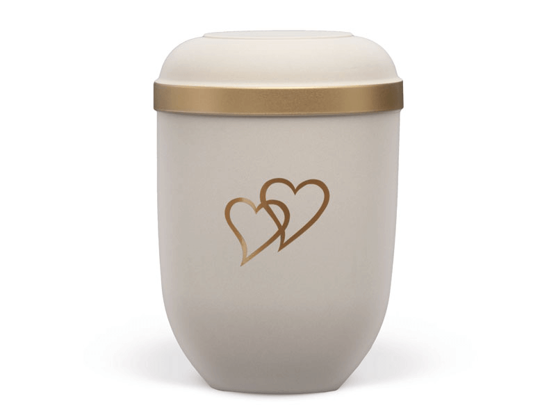 Cream-colored cremation urn with gold trim and two intertwined hearts.