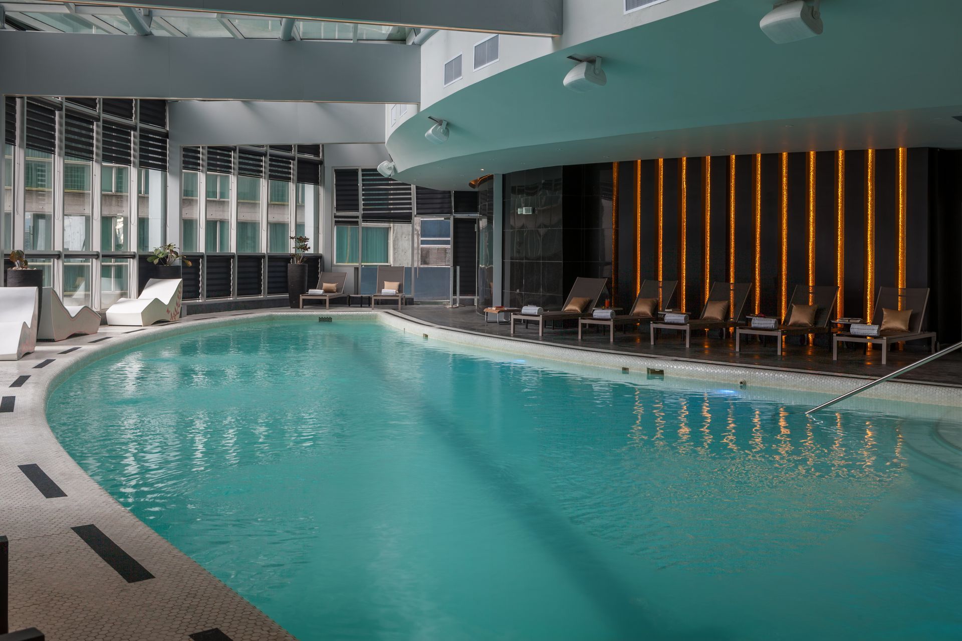 Una gran piscina cubierta está iluminada por la noche en un hotel.