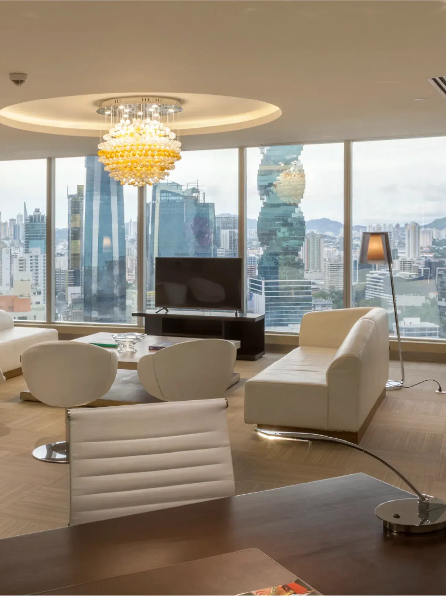 Un salón con muebles blancos y una televisión de pantalla plana.