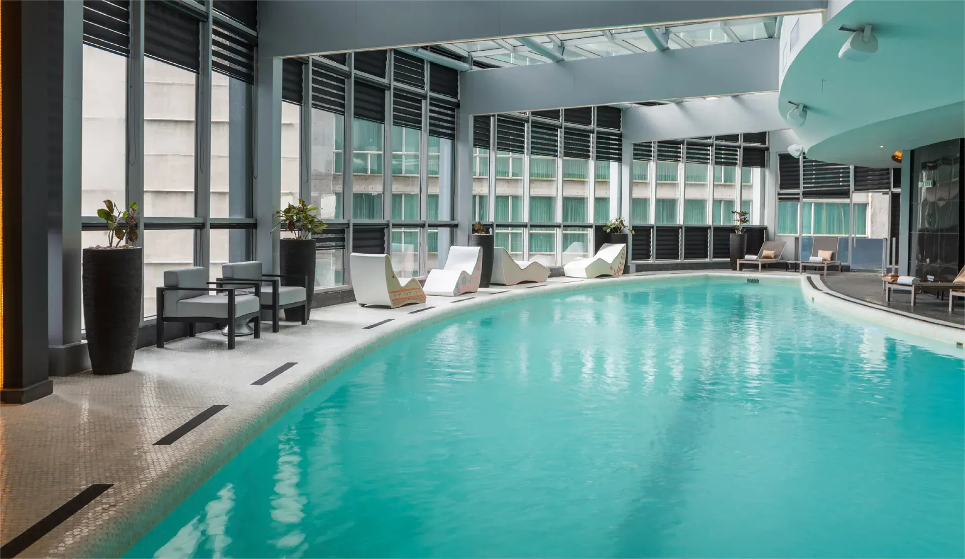 Una gran piscina cubierta está iluminada por la noche en un hotel.