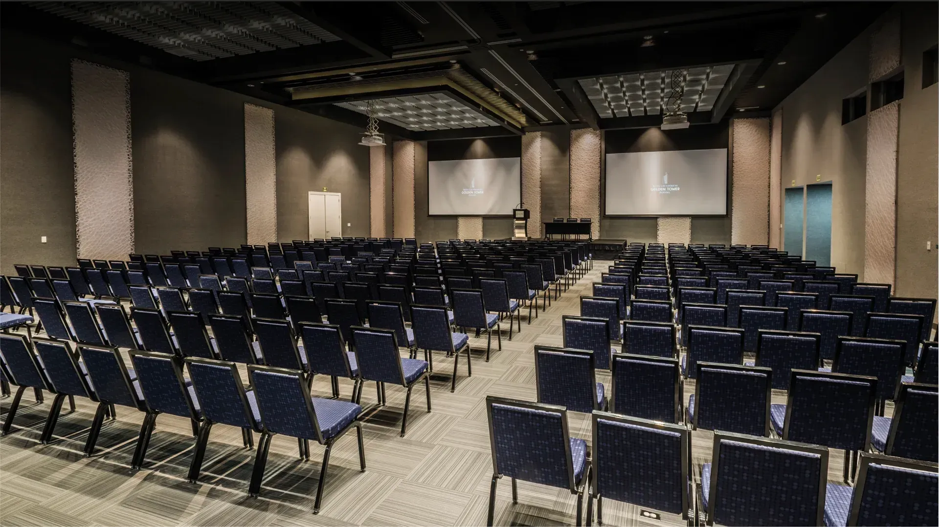 Un gran auditorio con sillas azules y un podio.