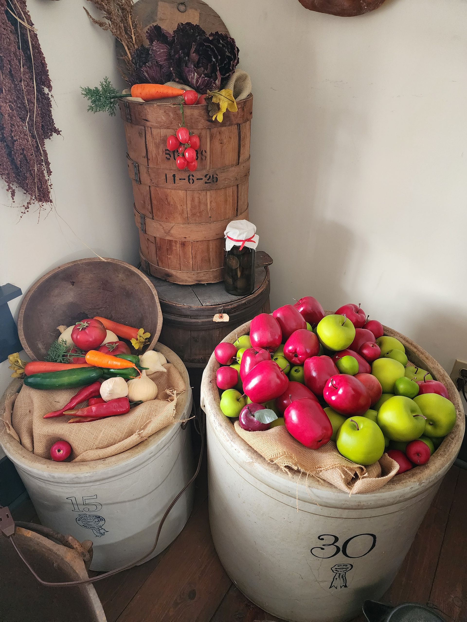 Buckets of colorful peppers and fruit arranged indoors as a harvest display