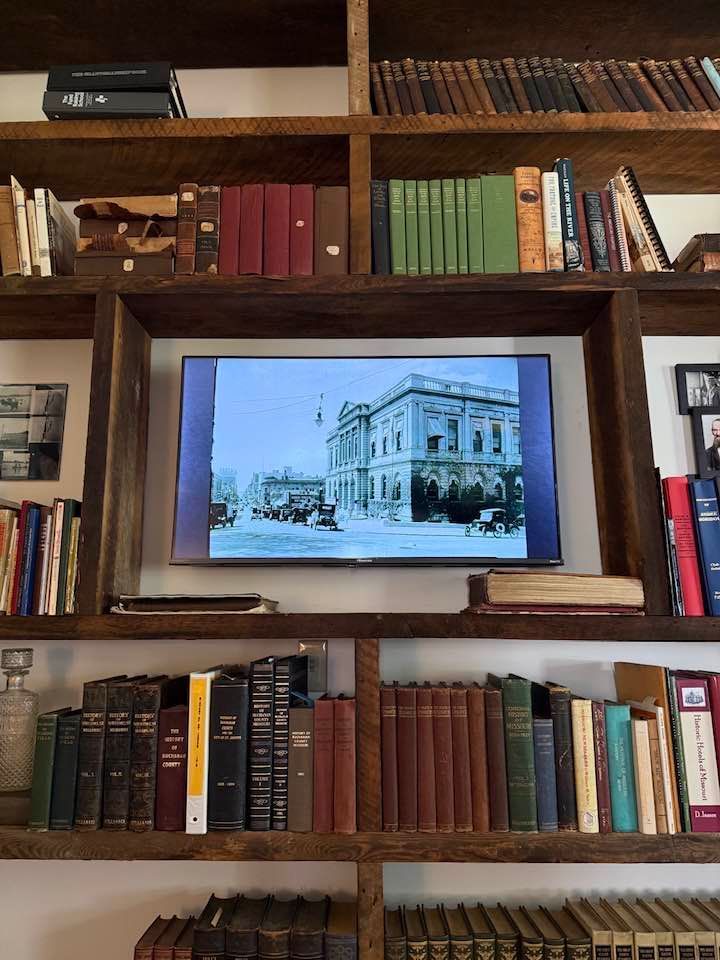 Bookshelf with books framing a TV displaying a black-and-white street scene of a historic building