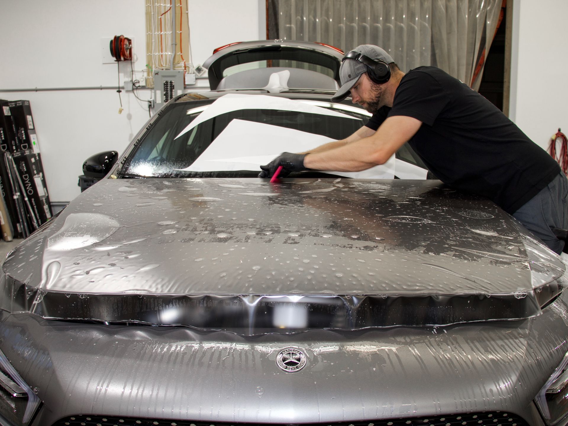 A man is working on the hood of a car in a garage.