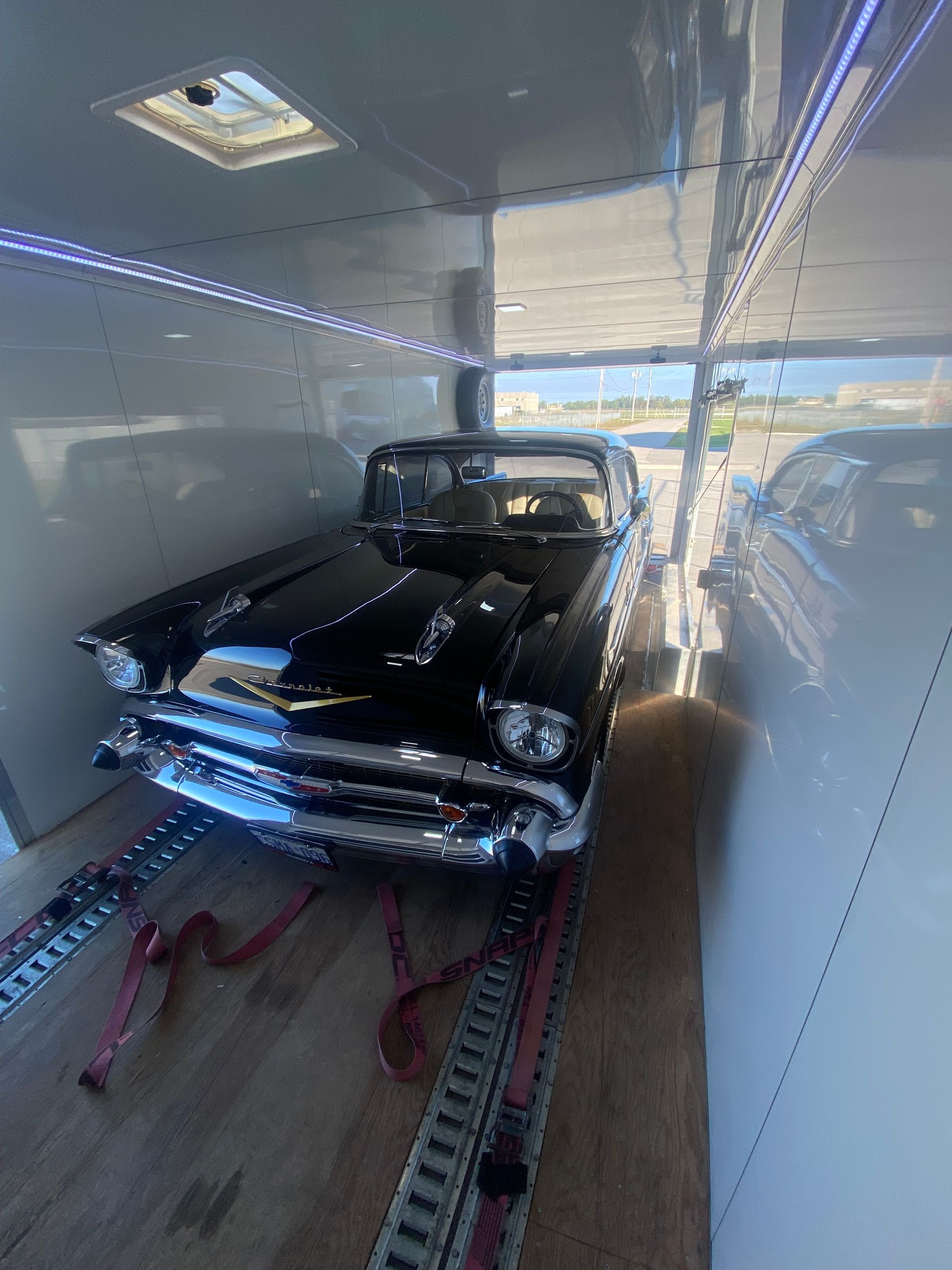 A black car is sitting inside of a trailer.