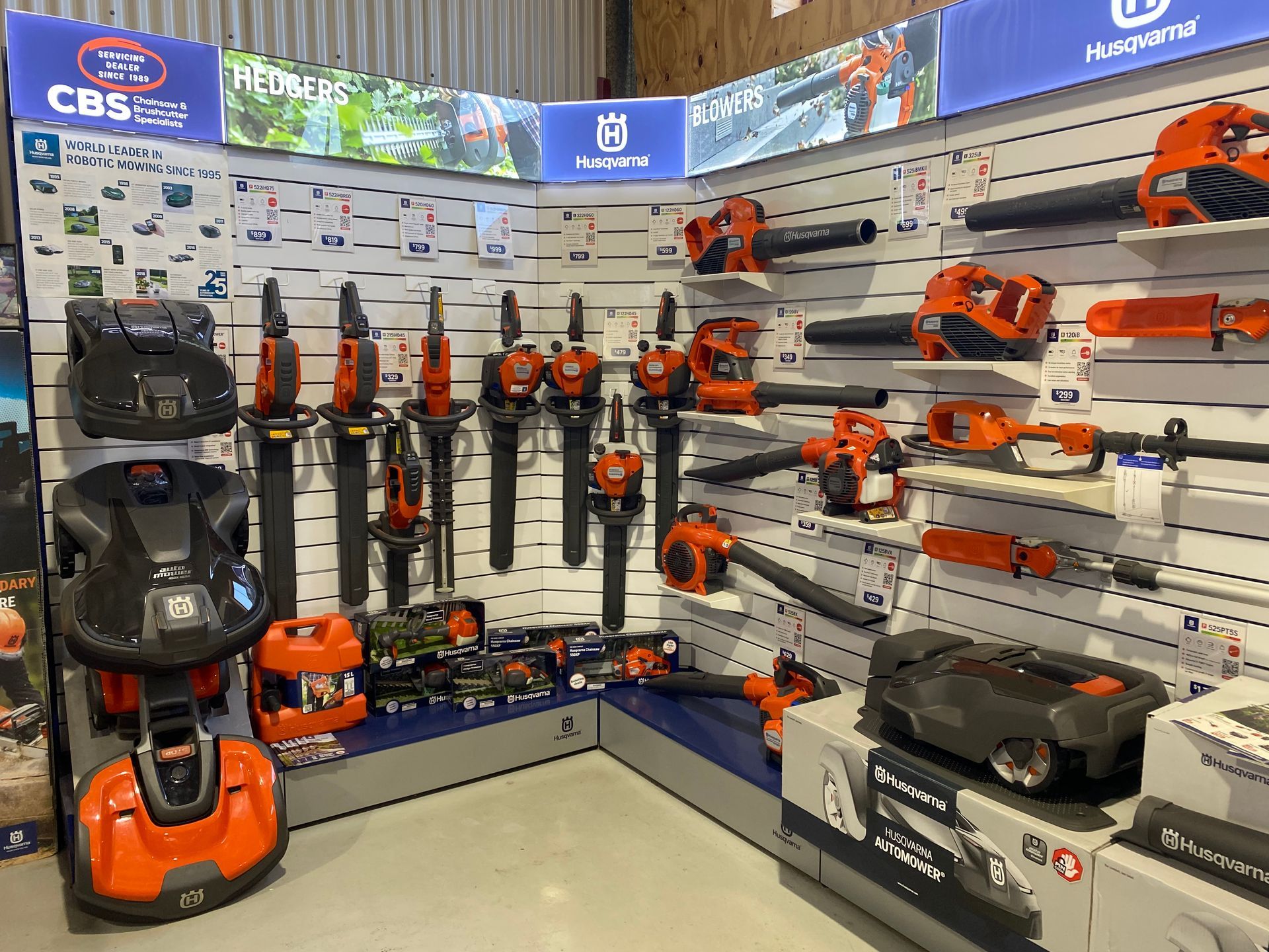 Husqvarna power tool display in a store. Blowers and robotic lawn mowers in orange and black. — CBS Chainsaw & Brushcutter Specialists - HUSQVARNA in Wauchope, NSW
