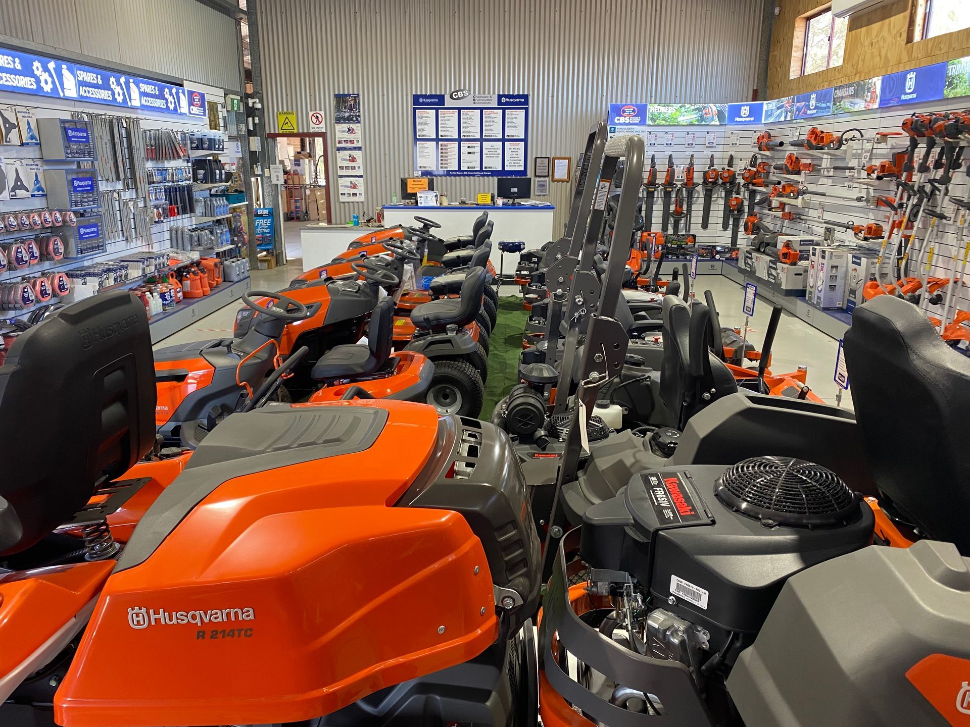 Inside a hardware store, various riding lawnmowers displayed in rows, with tools and equipment in the background. — CBS Chainsaw & Brushcutter Specialists - HUSQVARNA in Wauchope, NSW