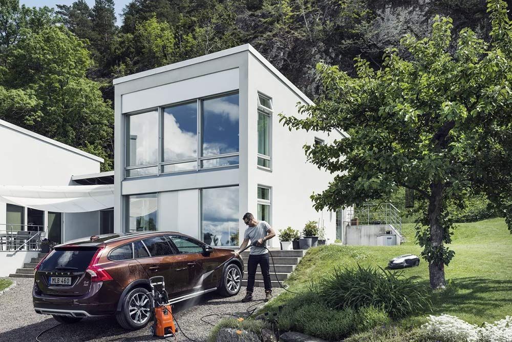 A Man Is Washing a Car in Front of A House — CBS Chainsaw & Brushcutter Specialists - HUSQVARNA in Wauchope, NSW