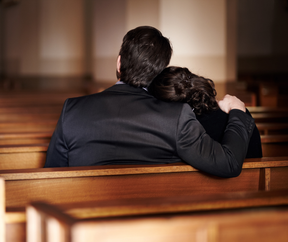 Son and his mother in a church pew after a simple and intimate funeral service.