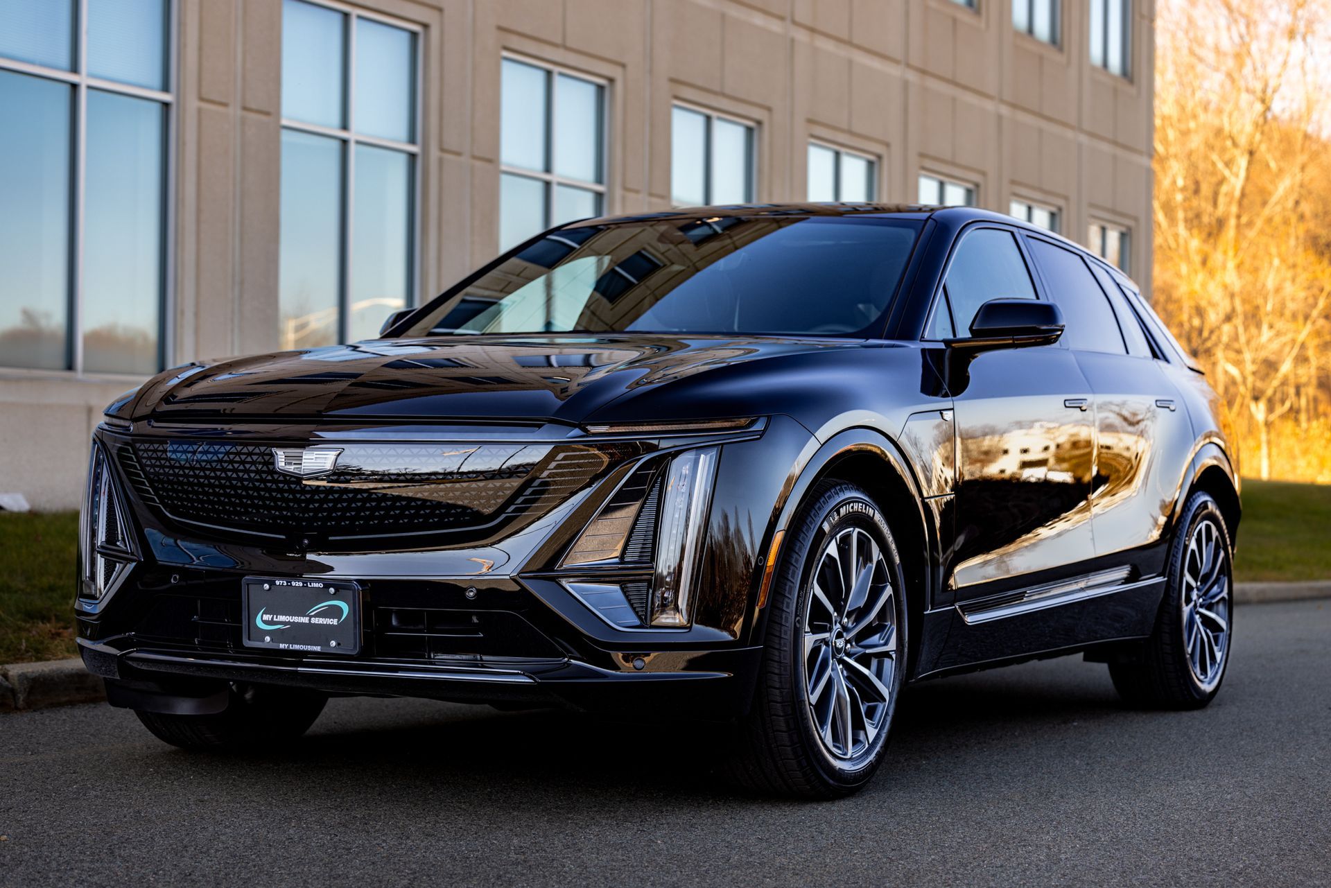 A black EV Limosine is parked in front of a building.