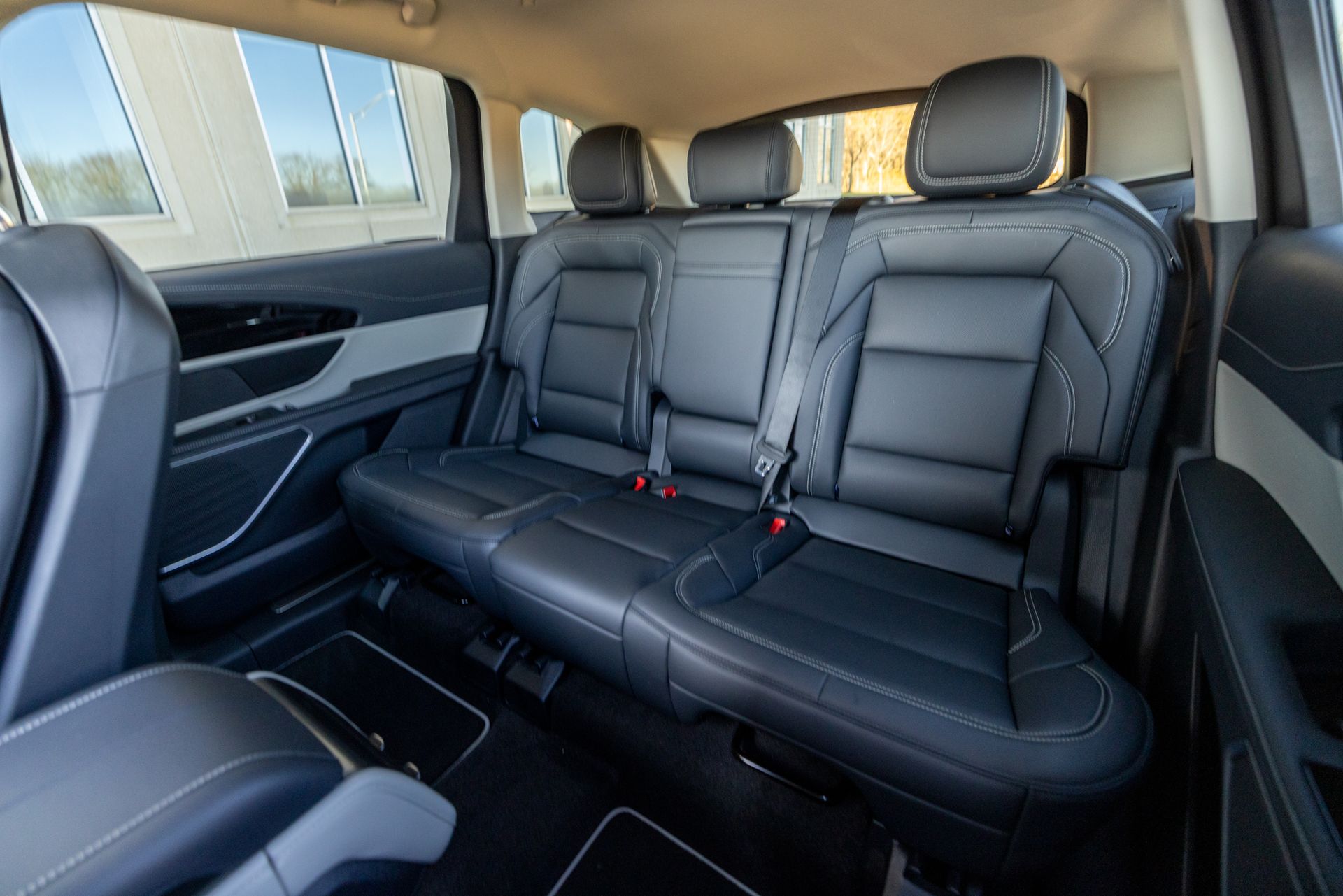 The back seat of a car with three seats and a seat belt.