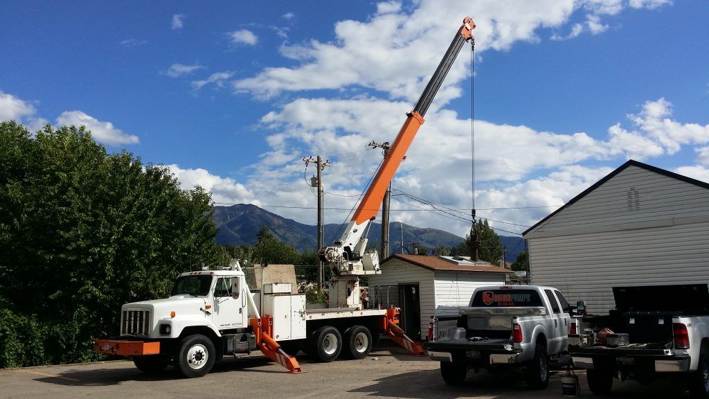 A truck with a crane attached to it is parked in front of a building.