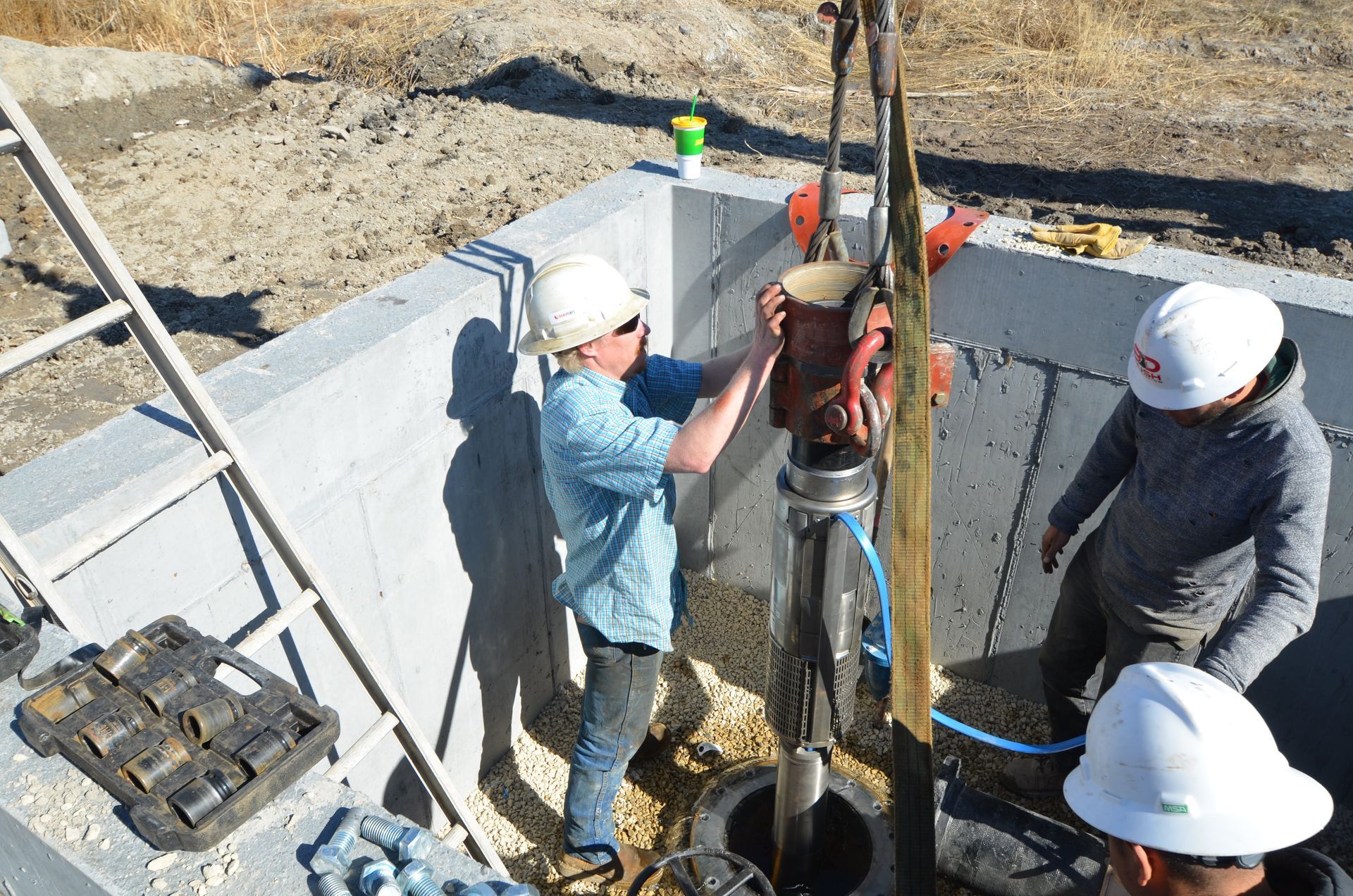 A group of construction workers are working on a well.