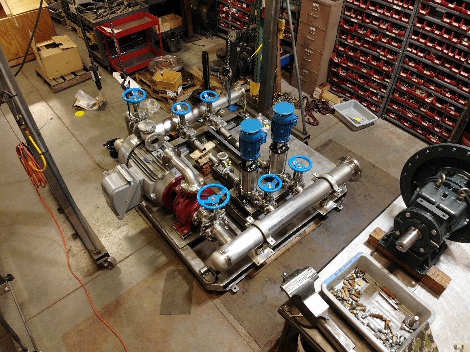 Industrial machinery with blue valves and silver pipes in a workshop setting.