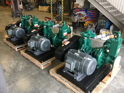 Several green industrial generators on wooden pallets in a warehouse.